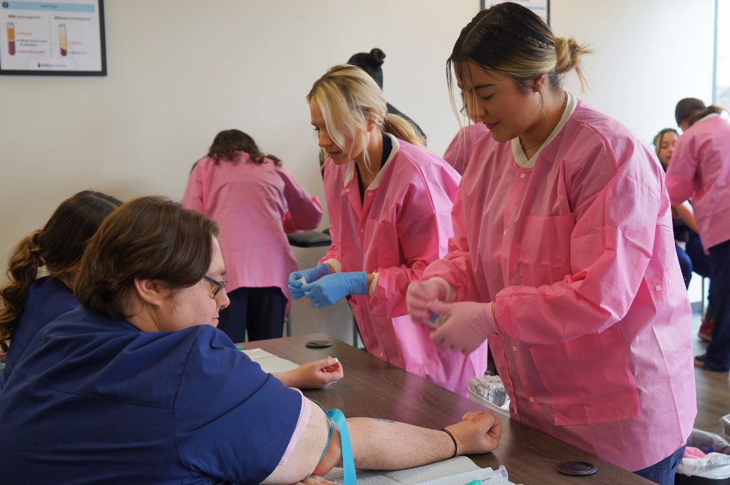 Phlebotomy students in Monterey County practicing blood draw skills during hands-on training.