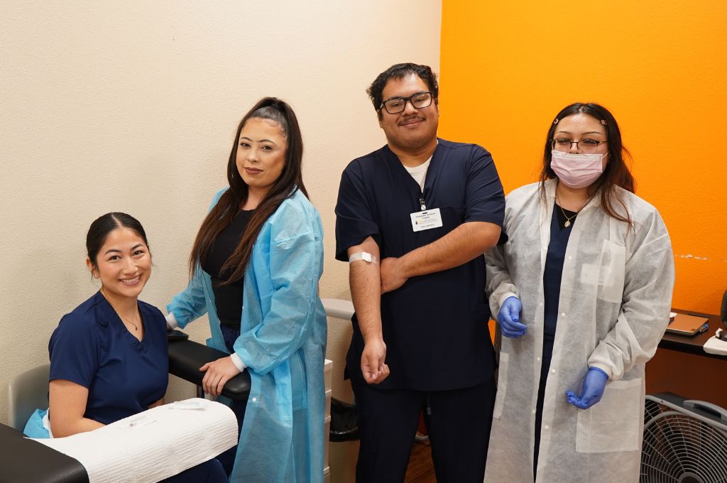 Group of Sacramento phlebotomy students posing after completing blood draw practice at CALRegional.