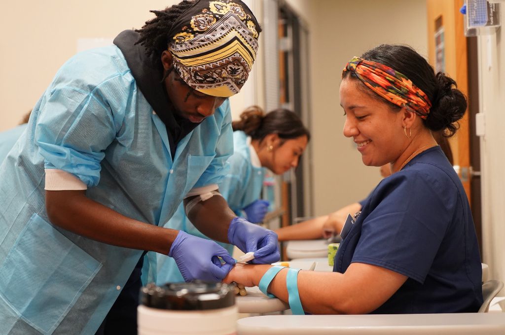 Phlebotomy student practicing blood draw techniques during hands-on clinical training.