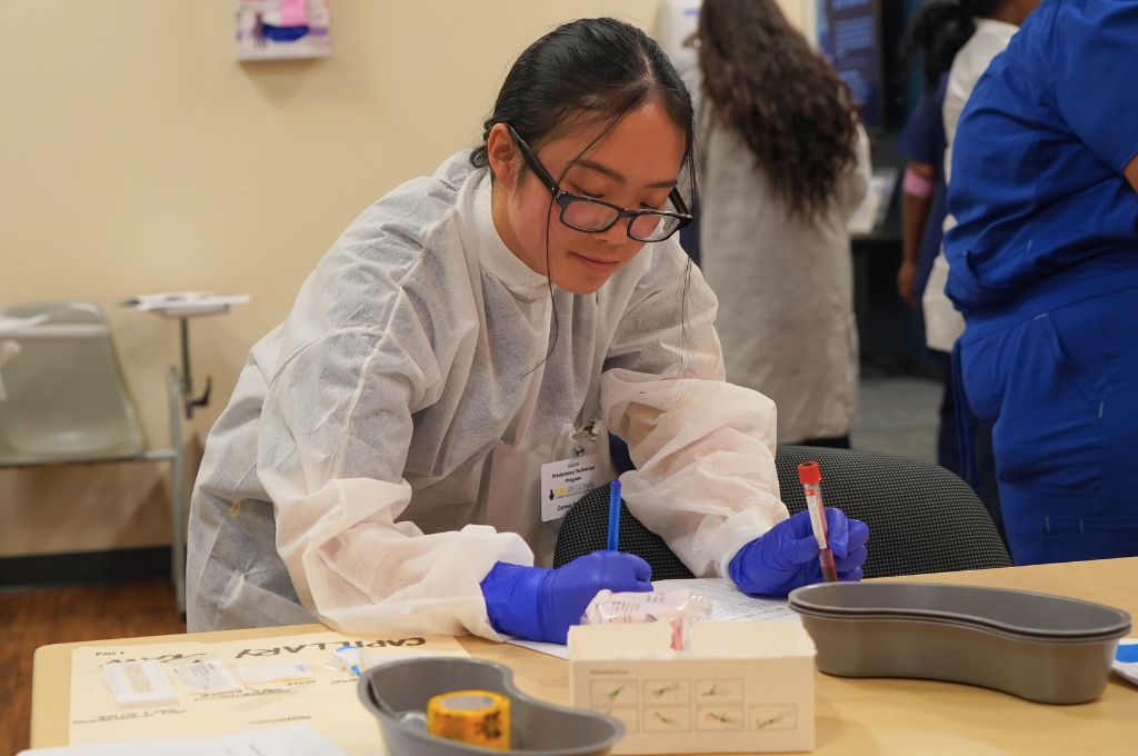 Phlebotomy student labeling a blood sample during classroom and lab training.
