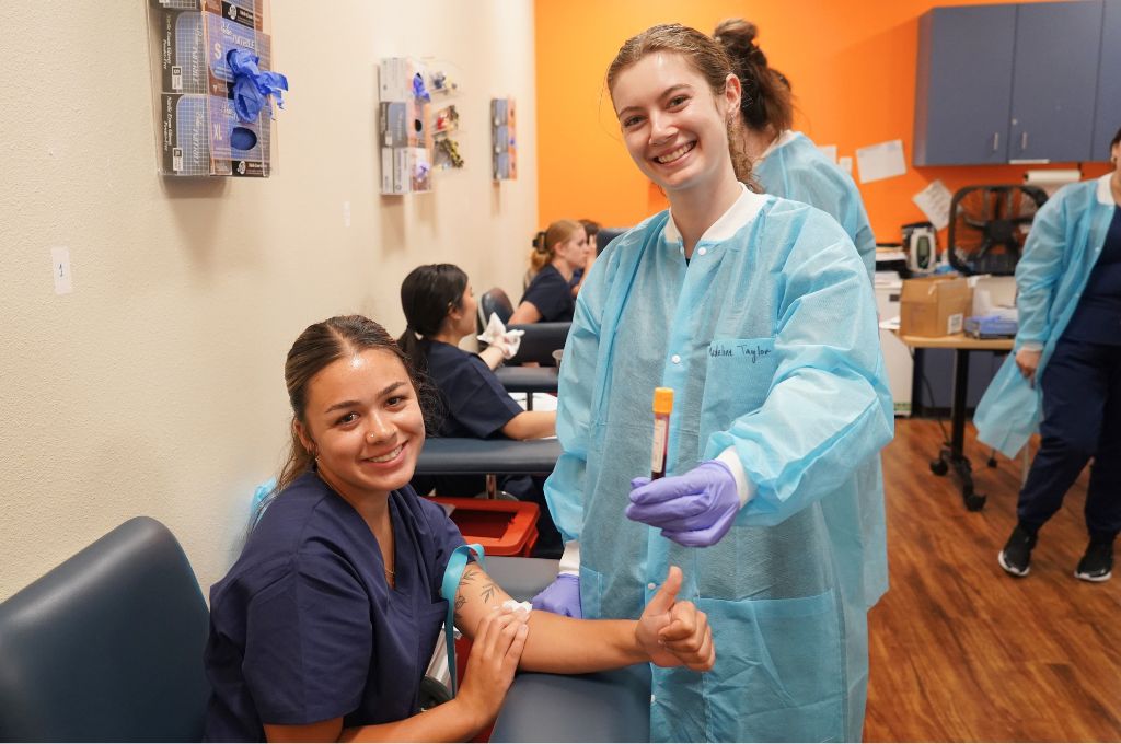 Phlebotomy student giving a thumbs up after a successful blood draw in training